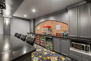 Entertainment area featuring a long black countertop, recessed lighting, and a brick-finish accent wall