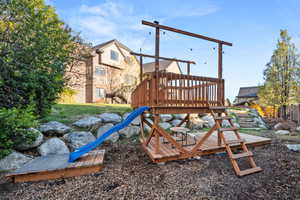 Multi-level wooden play structure featuring a slide and sandpit