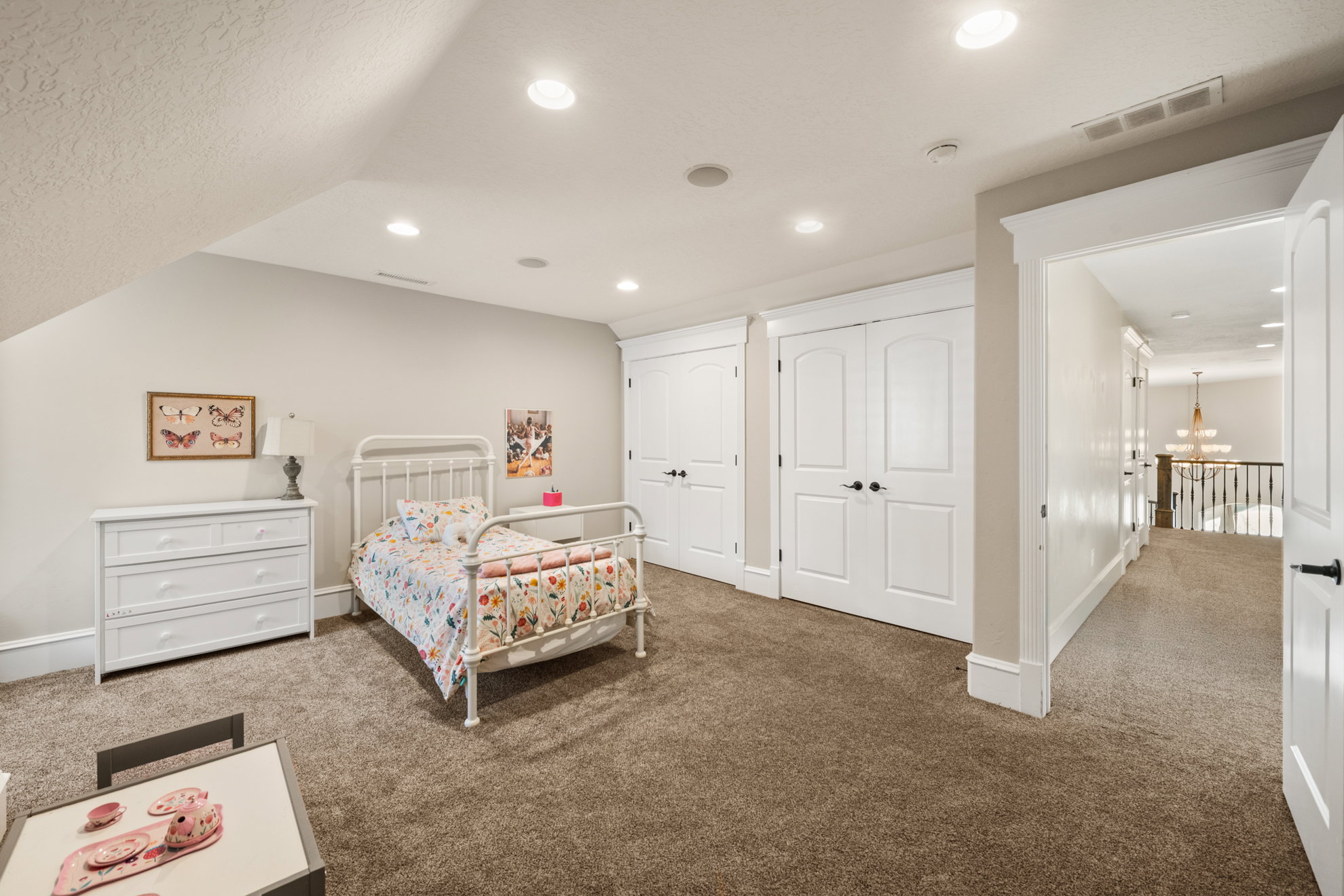 Carpeted room featuring an angled ceiling with recessed lighting, two double-door closets with dark hardware, and a hallway entry