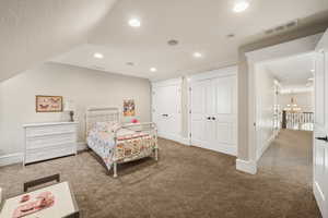 Carpeted room featuring an angled ceiling with recessed lighting, two double-door closets with dark hardware, and a hallway entry