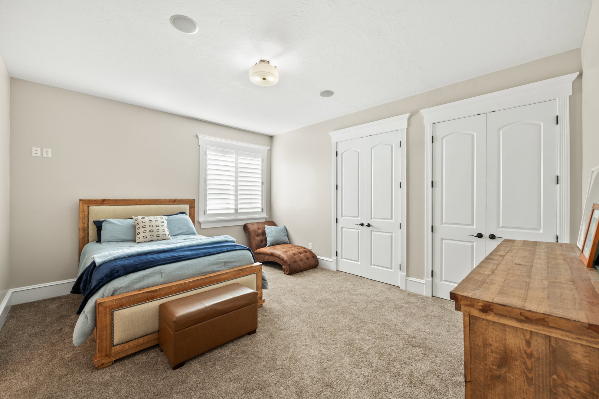 Carpeted room featuring a window with white louvered shutters, ceiling-mounted light fixture, and recessed lighting
