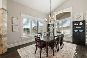 Dining area featuring vaulted ceilings and dark wood-finish flooring