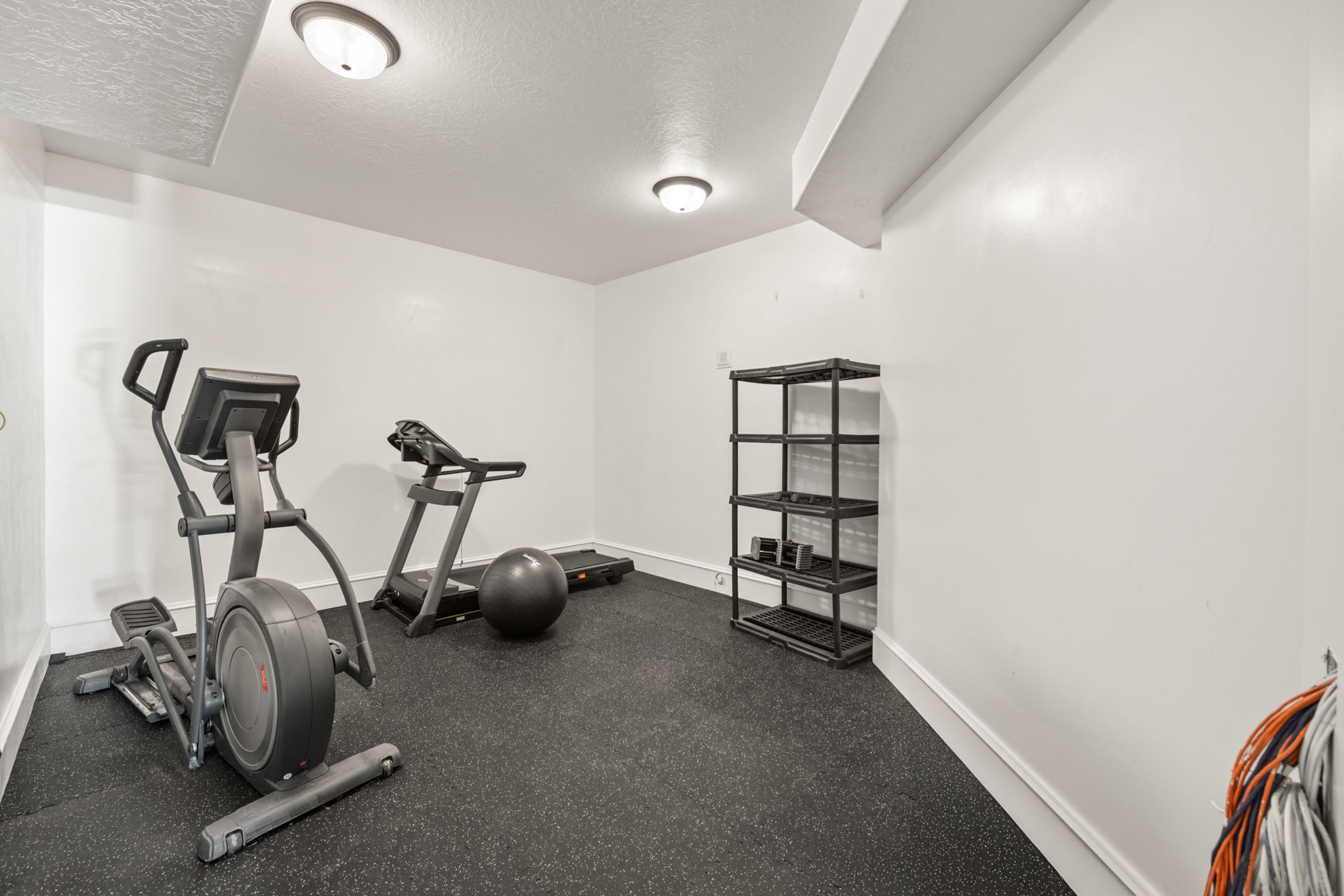 Dedicated fitness area featuring durable rubber flooring, recessed lighting, and crisp white walls