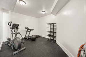 Dedicated fitness area featuring durable rubber flooring, recessed lighting, and crisp white walls