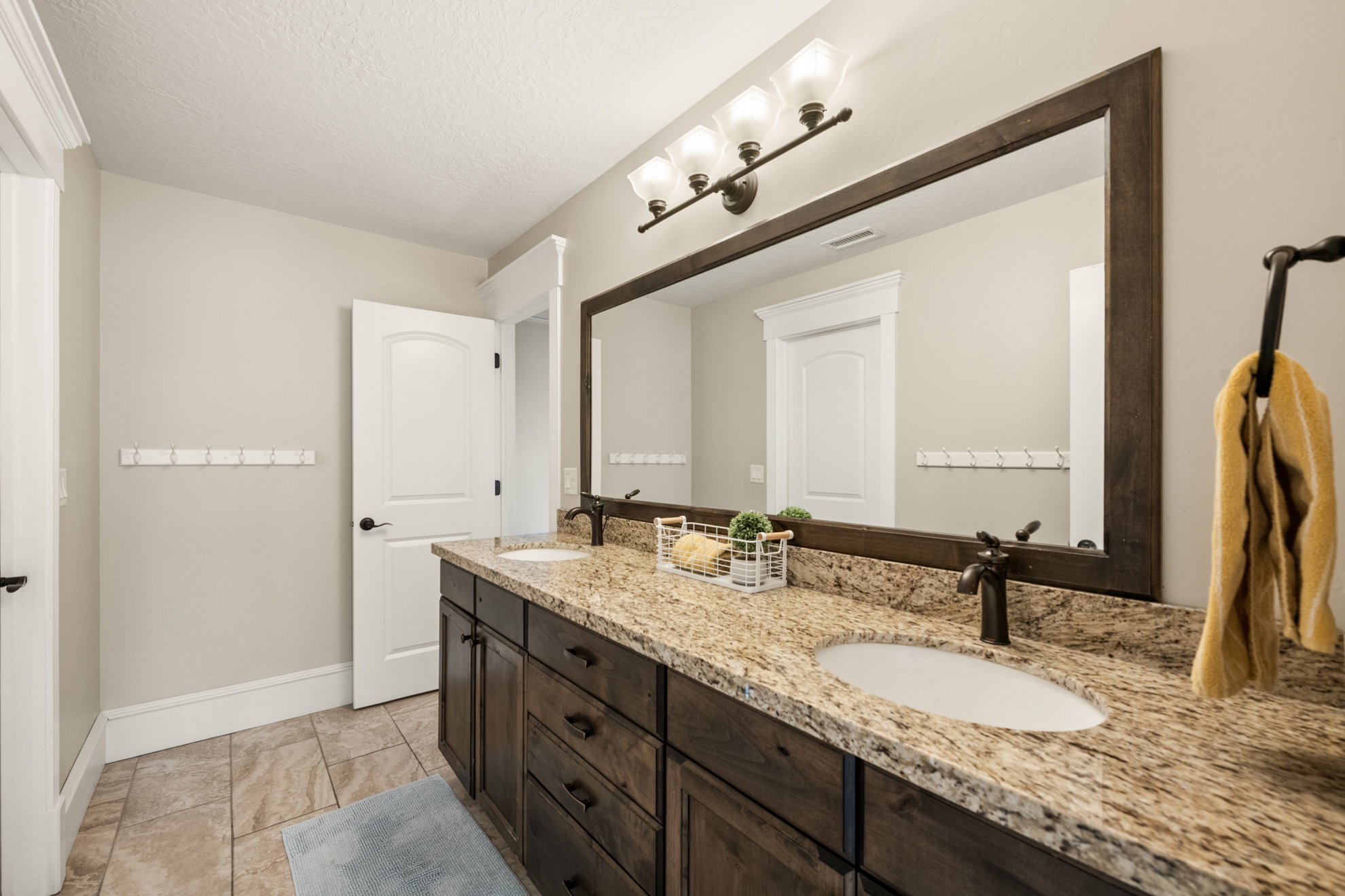 Double vanity featuring a granite countertop, dual undermount sinks, and dark wood cabinetry