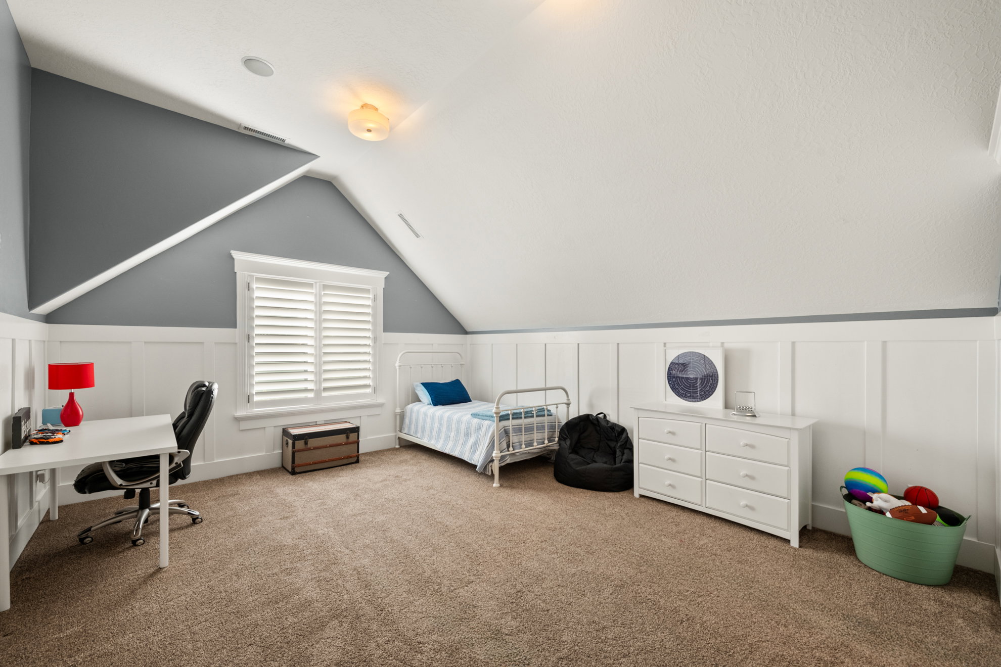 Carpeted room featuring a window with white plantation shutters, board and batten wainscoting, and a sloped ceiling with recessed lighting