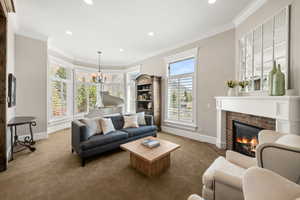 Living area featuring a brick fireplace with a white mantel, bay windows with plantation shutters, crown molding, and recessed lighting