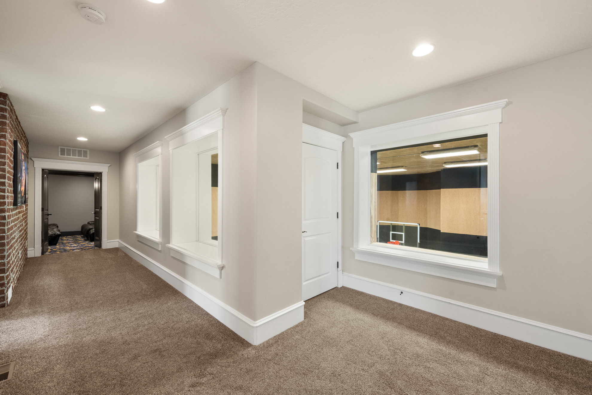 Hallway featuring plush carpeting, recessed lighting, and a brick accent wall