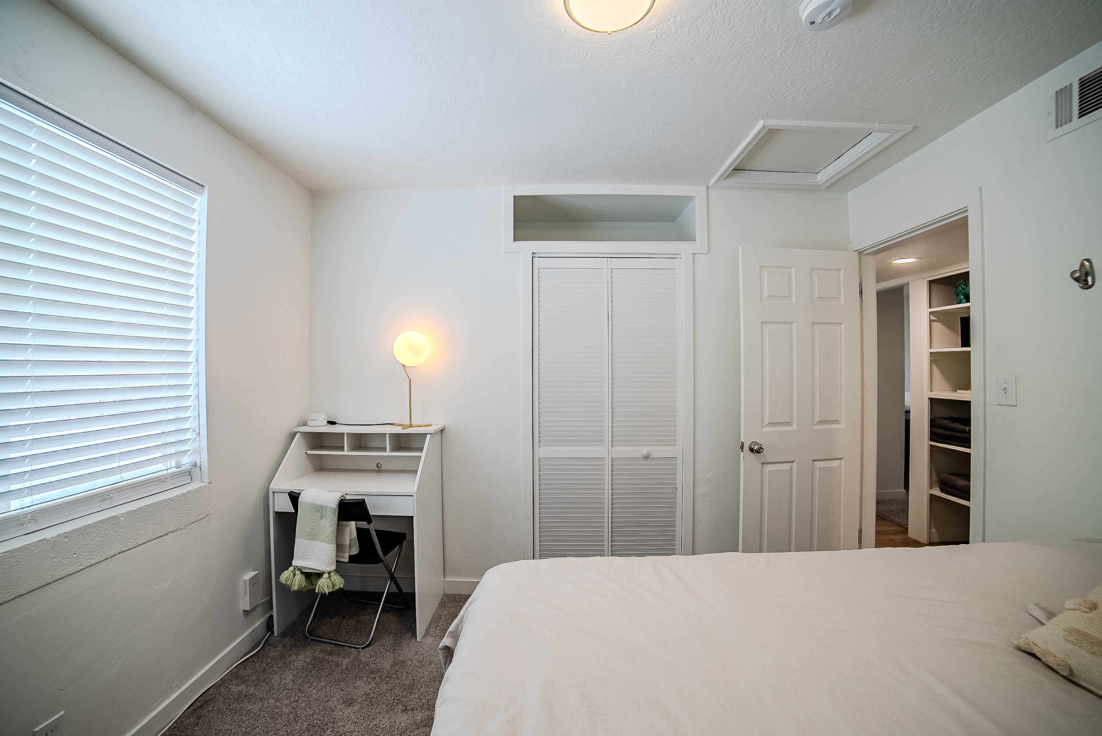 Bedroom featuring white walls, textured carpeting, and a window with blinds