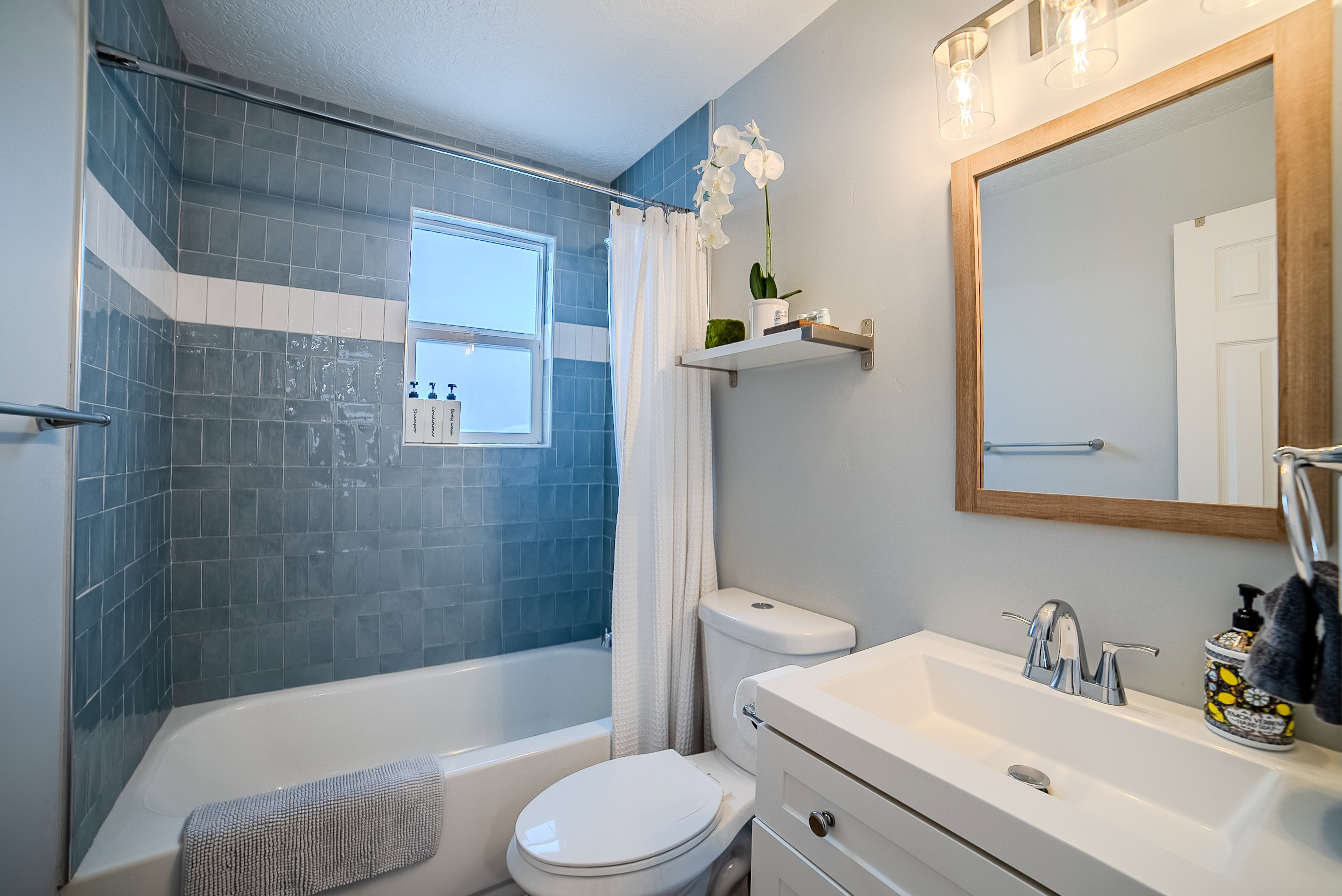 Bathroom featuring a white vanity with integrated sink, chrome faucet, and wood-framed mirror