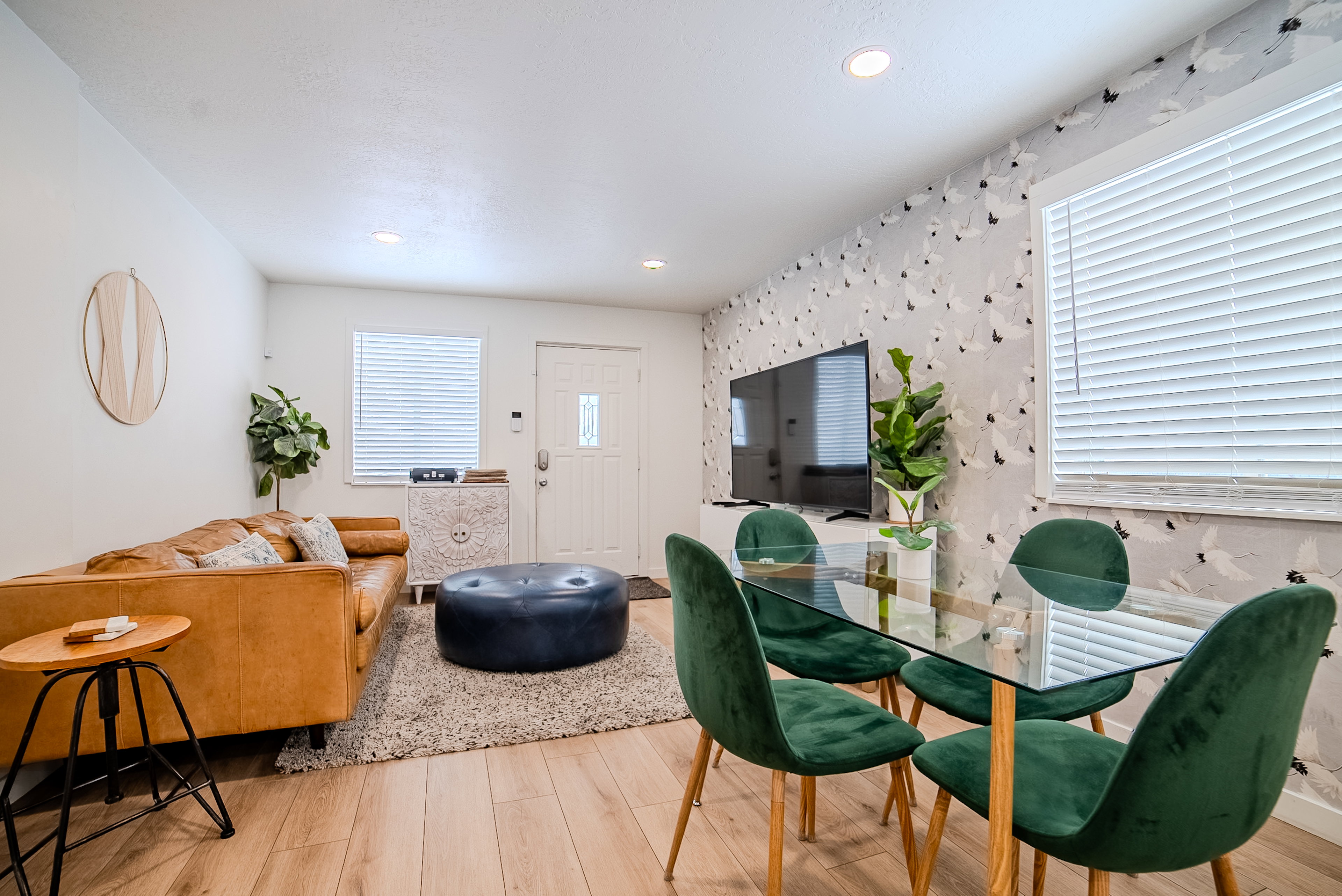 Open-concept living space featuring wood-finish flooring, recessed lighting, and a white entry door with a decorative glass panel