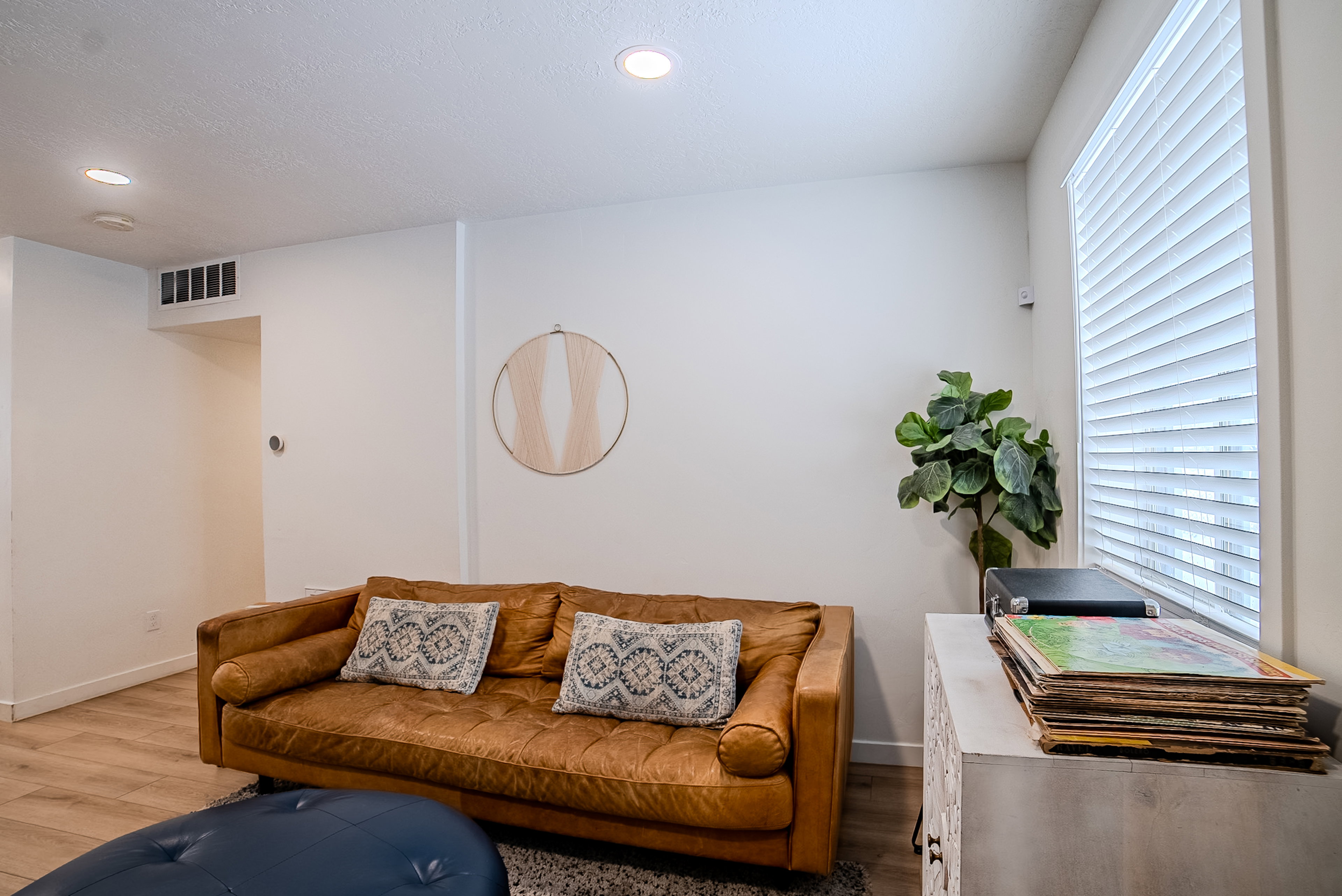 Recessed lighting illuminates this room featuring wood-finish flooring, white baseboards, and a window with horizontal blinds