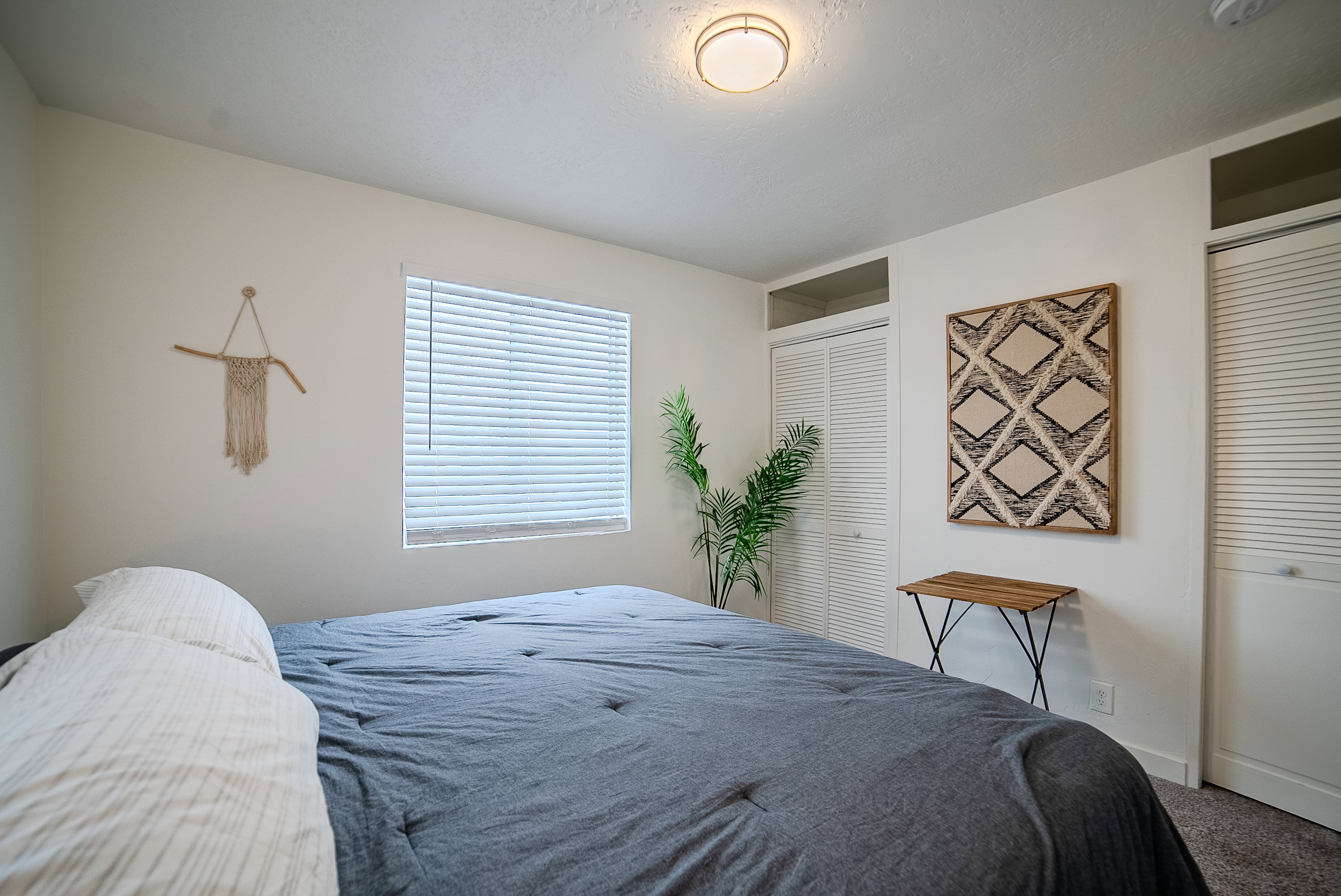 Bright room featuring a ceiling-mounted light fixture, a window with horizontal blinds, and carpeted flooring