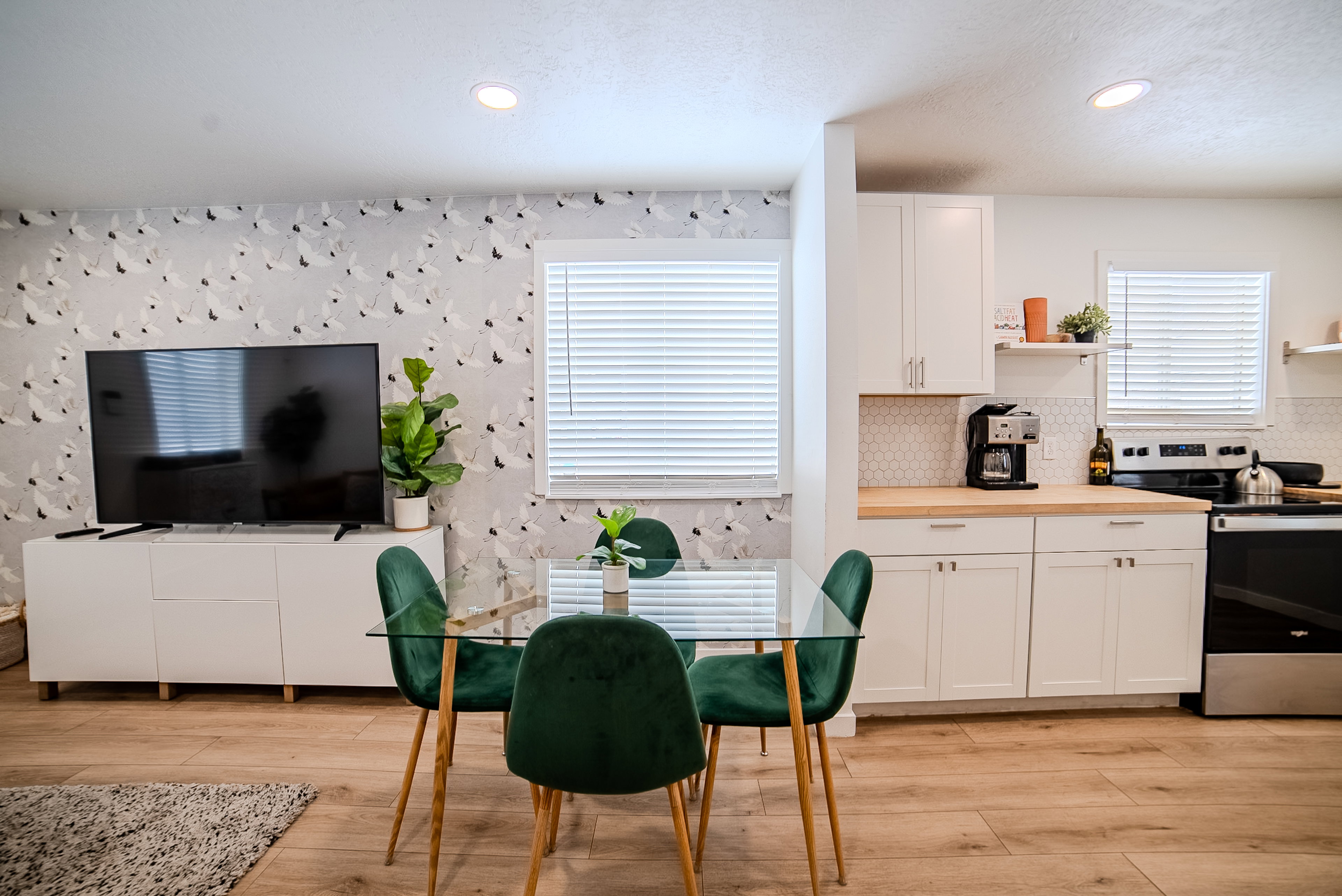 Open-concept living space featuring wood-finish flooring, recessed lighting, and a kitchen with white cabinetry, wood countertops, and a hexagonal tile backsplash