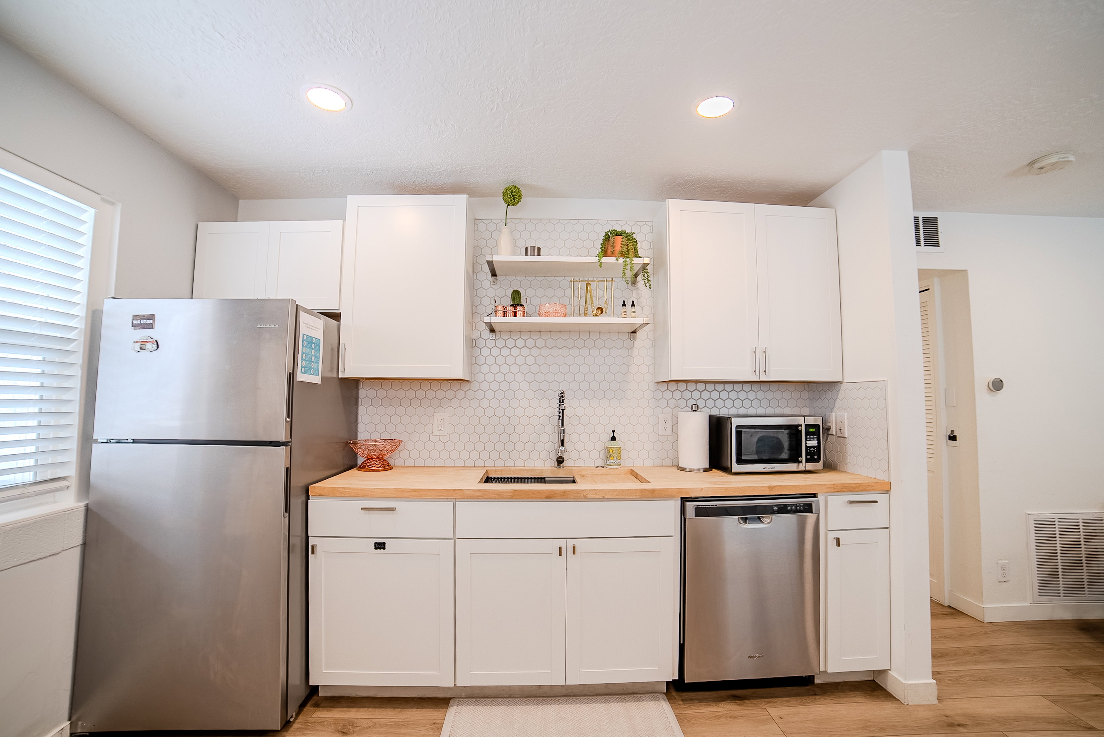 Kitchenette featuring white shaker-style cabinetry, wood-finish countertops, and a white hexagonal tile backsplash