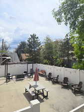 Paved patio space featuring a white privacy fence, string lighting, and a dark-toned pergola
