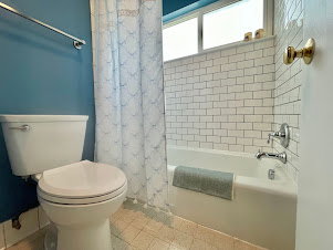 Bathroom with white subway tile shower surround, chrome fixtures, and a dual-pane window above the tub
