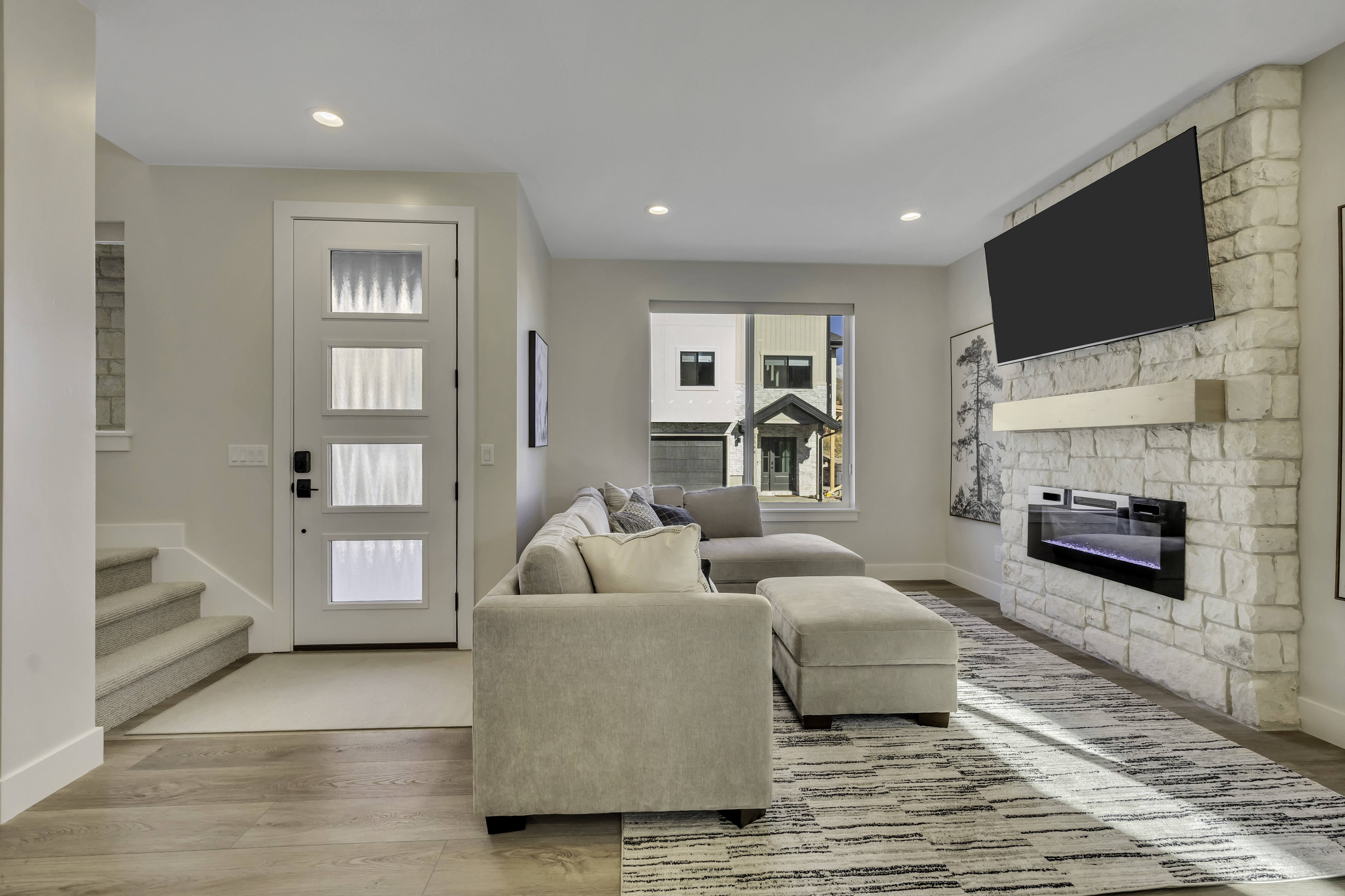Living area featuring light wood-style flooring, a stone fireplace, and recessed lighting