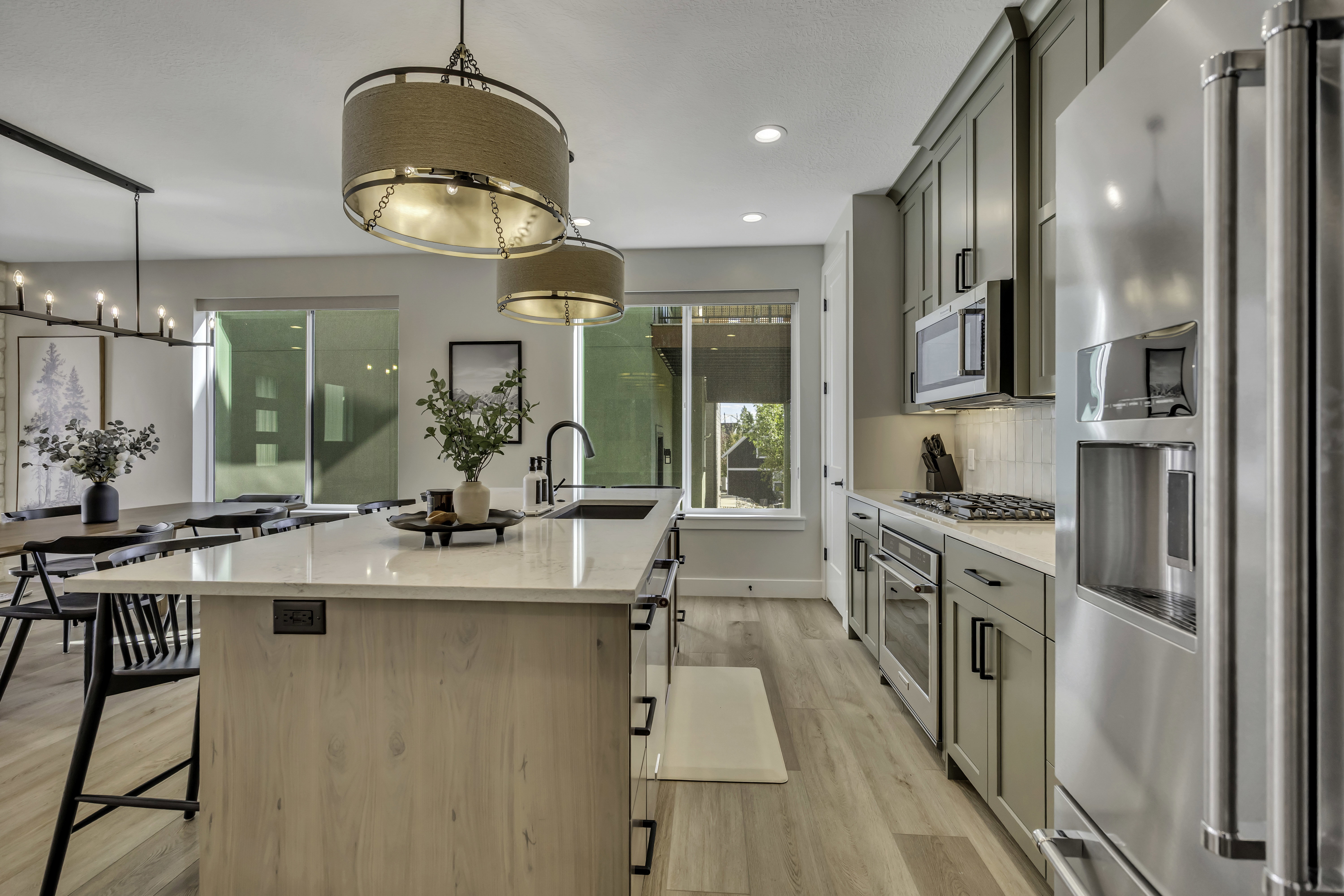 Kitchen with stainless steel appliances, a center island with sink, a kitchen bar, light stone counters, and light wood-style floors