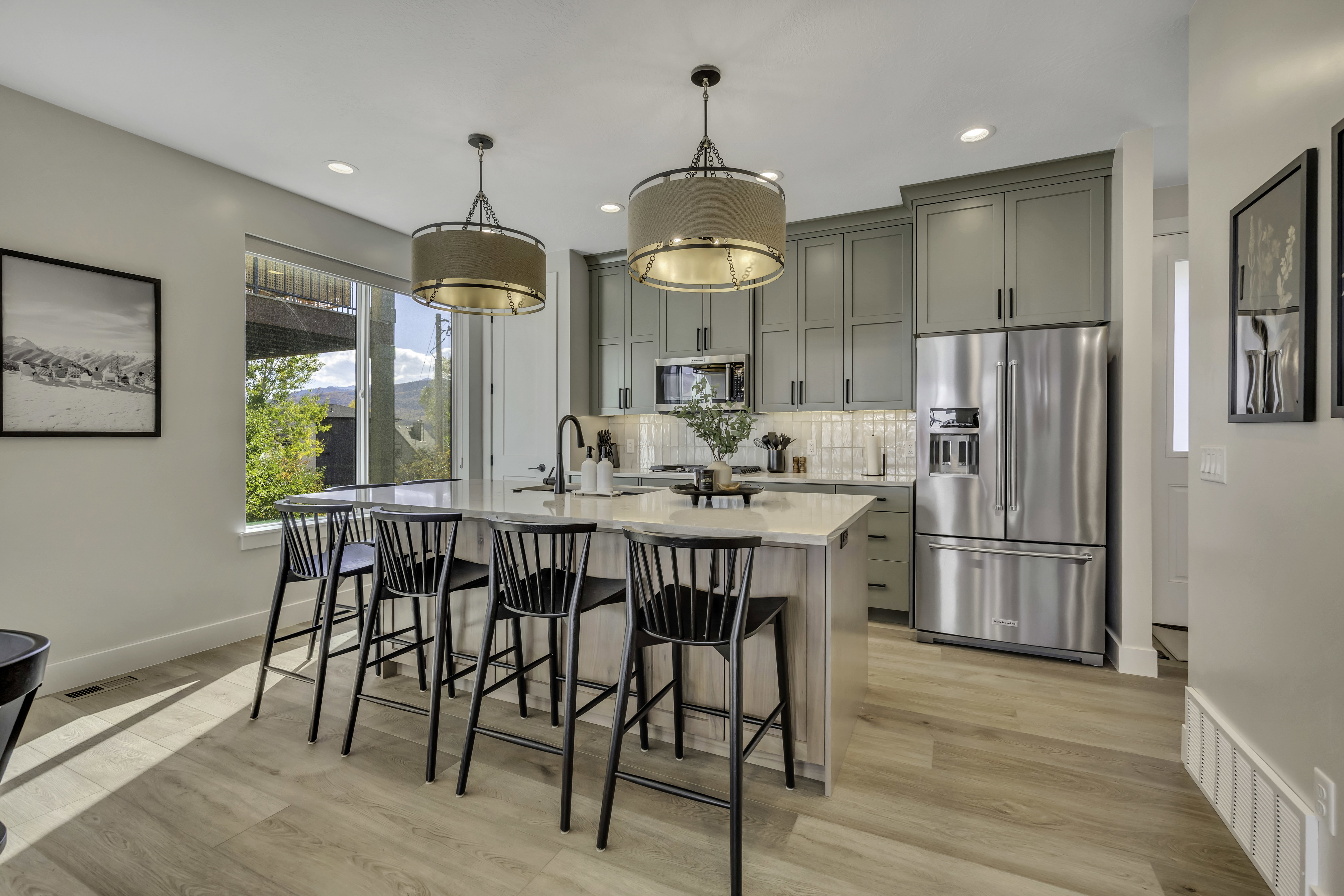 Kitchen with stainless steel appliances, a center island with sink, light stone counters, light wood-style floors, and a breakfast bar