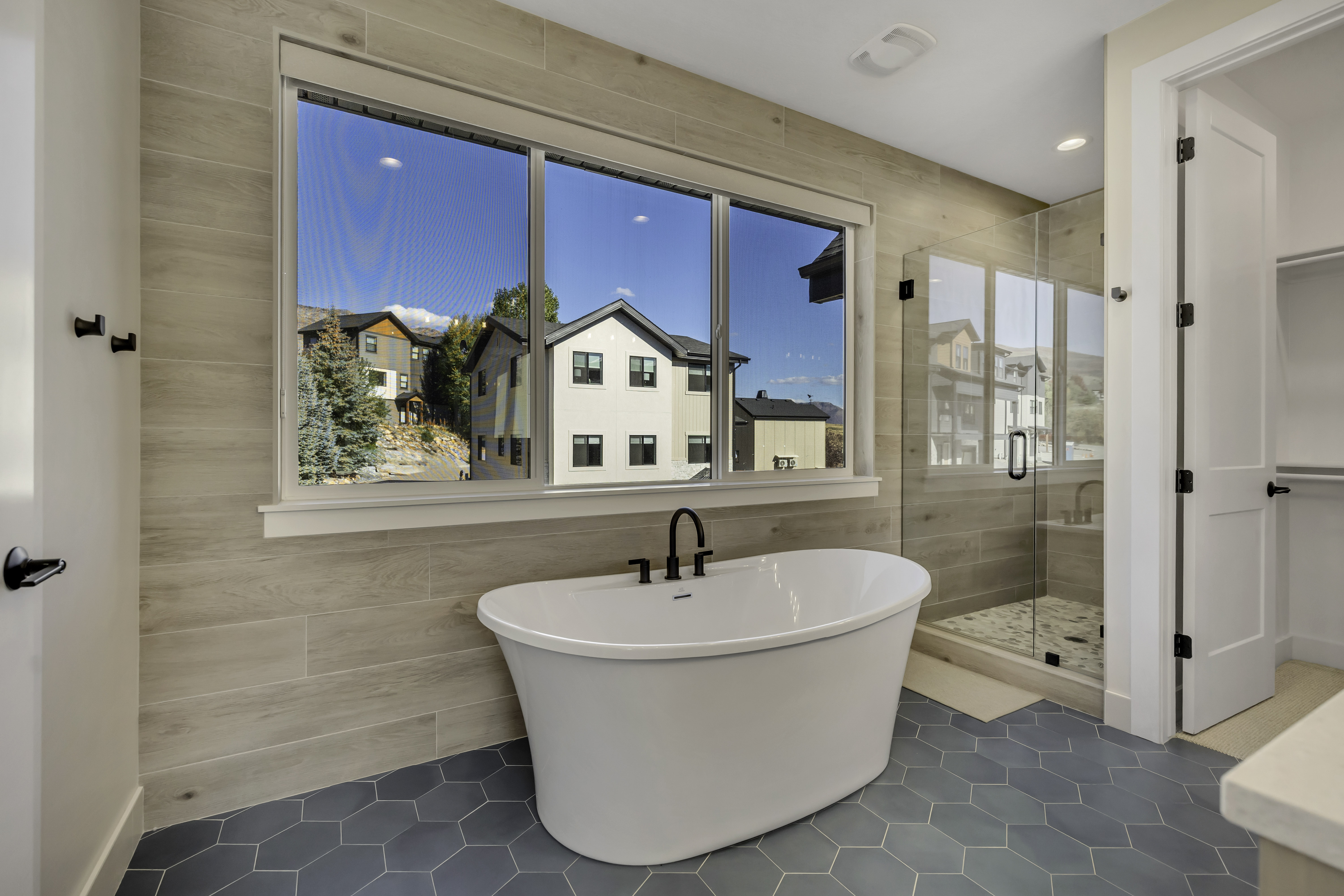 Full bathroom with a freestanding bath, tile patterned flooring, a stall shower, and tile walls