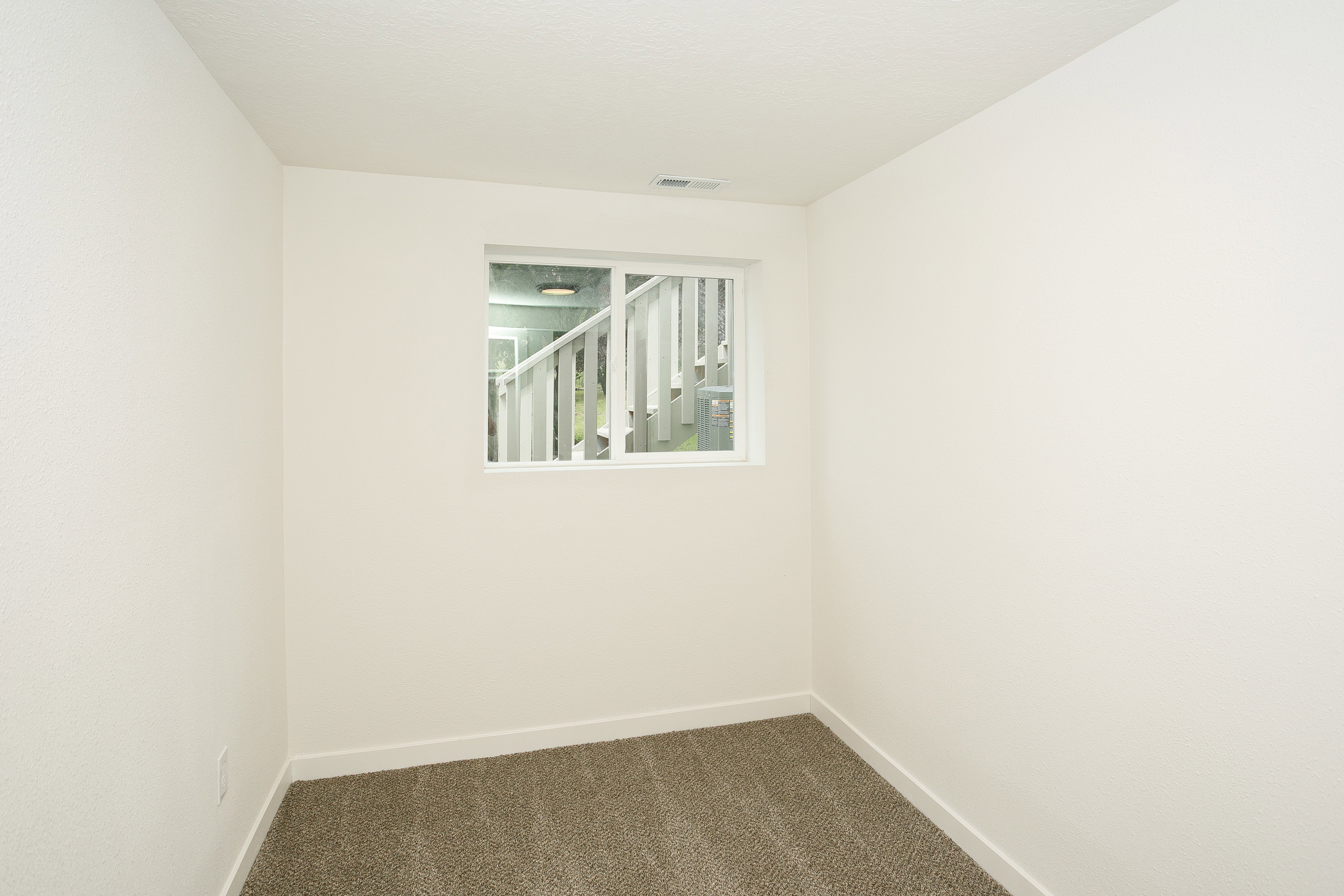 Neutral-toned interior room with light-colored walls and a window providing natural illumination