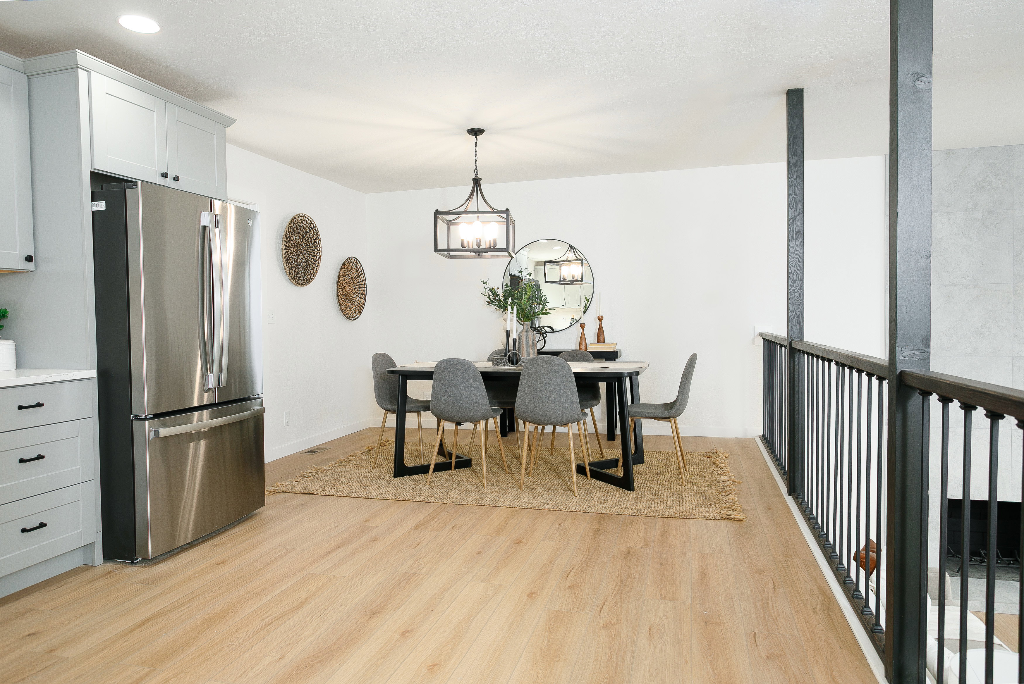 Spacious dining area featuring a contemporary chandelier, light wood-finish flooring, and crisp white walls