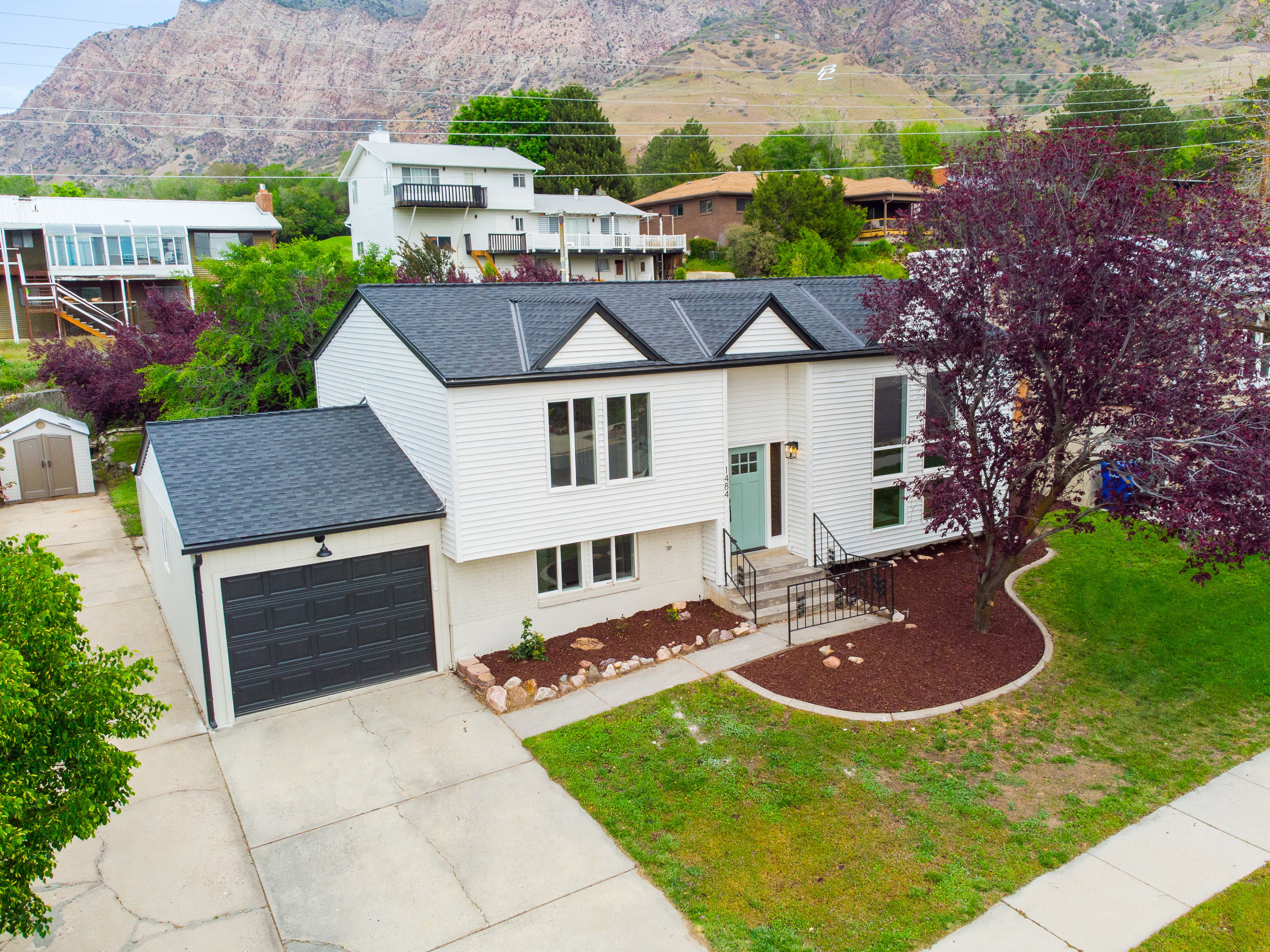 Split-level residence featuring white siding, a dark asphalt shingle roof, and a teal entry door
