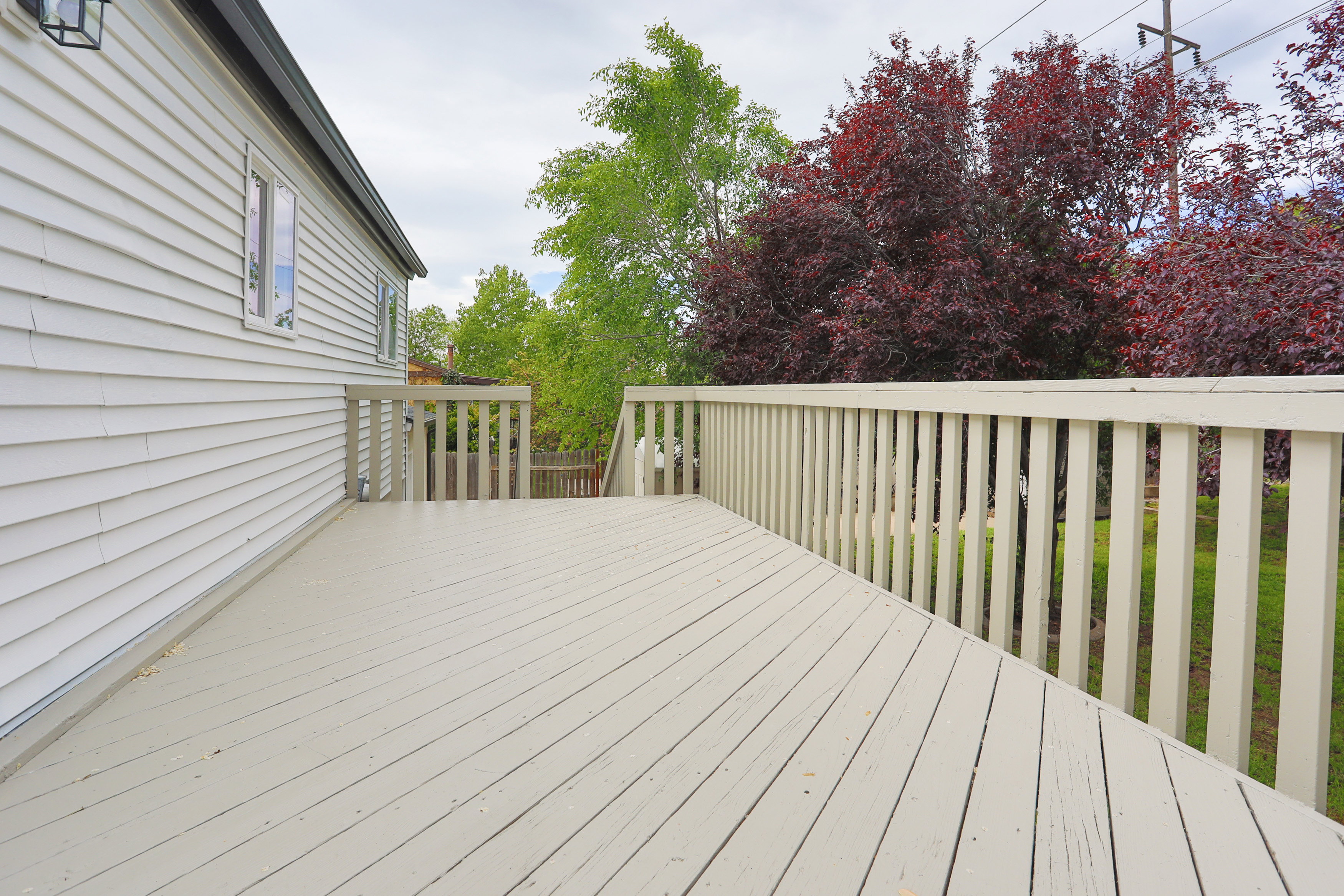Spacious outdoor deck featuring light-colored wood planks and a matching railing system