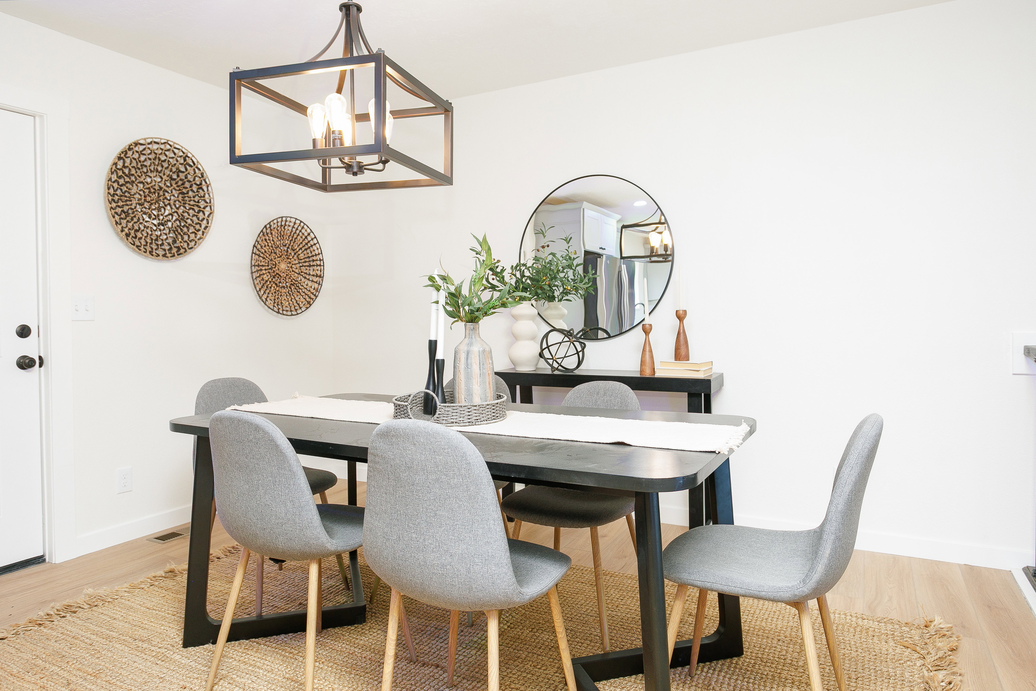 Dining area featuring wood-finish flooring, a contemporary chandelier, and a solid white door with black hardware