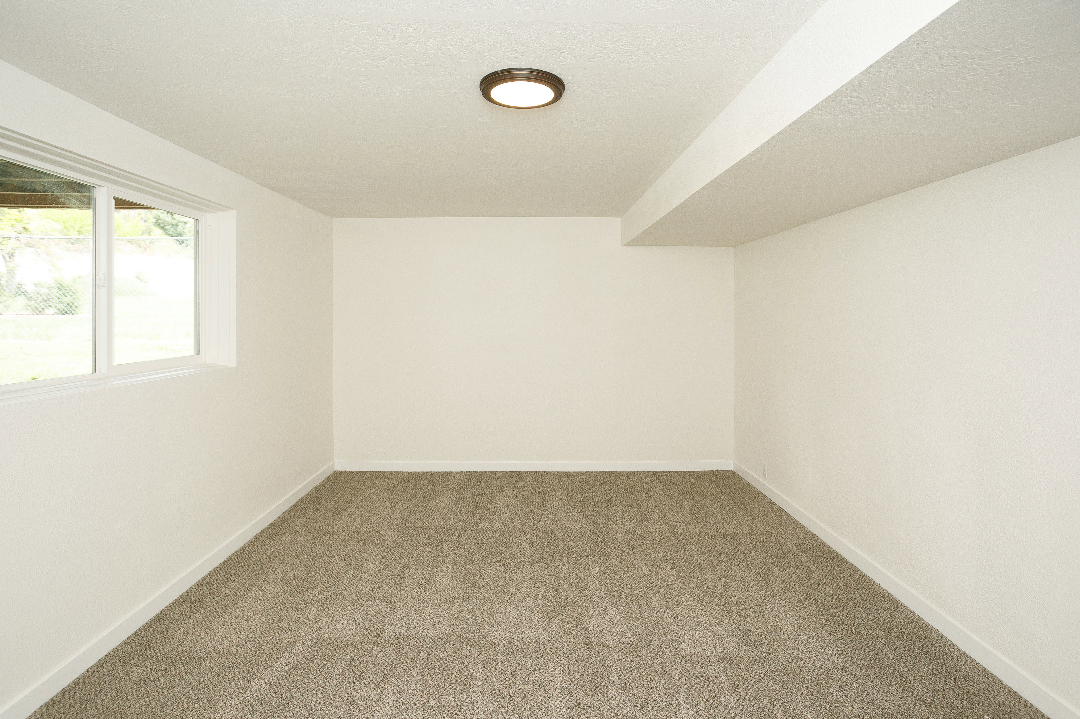 Neutral-toned carpet flooring complements light-colored walls in this spacious room