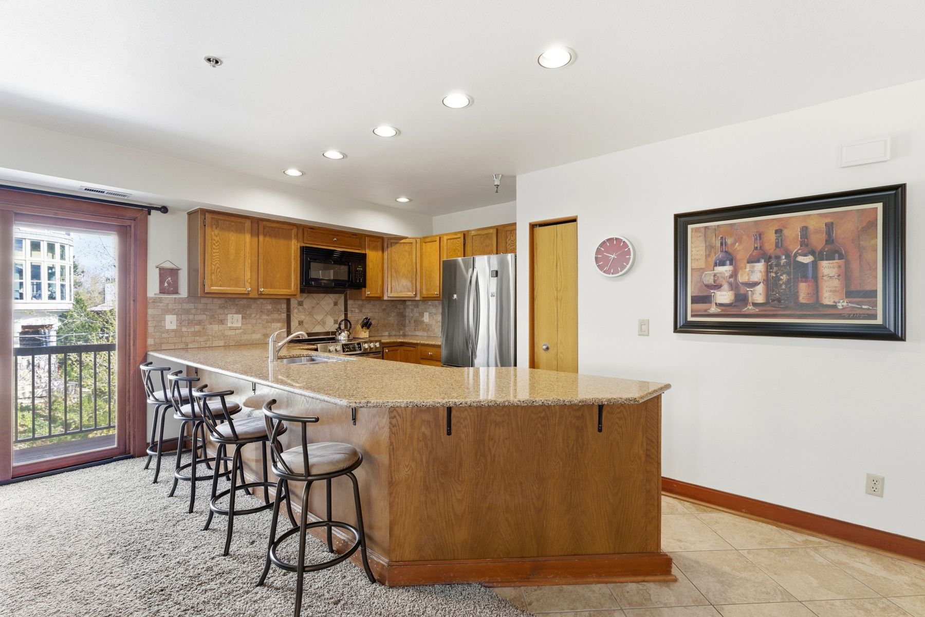 Spacious kitchen featuring a large island with seating, natural wood cabinetry, stainless steel appliances, recessed lighting, and a tile backsplash