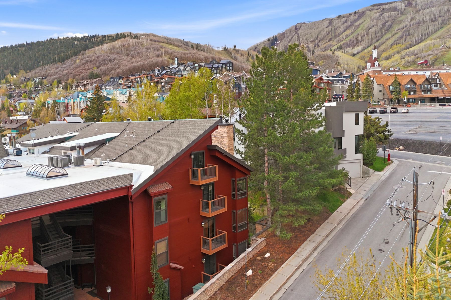 Multi-story property featuring a red siding exterior and multiple private balconies with wood railings