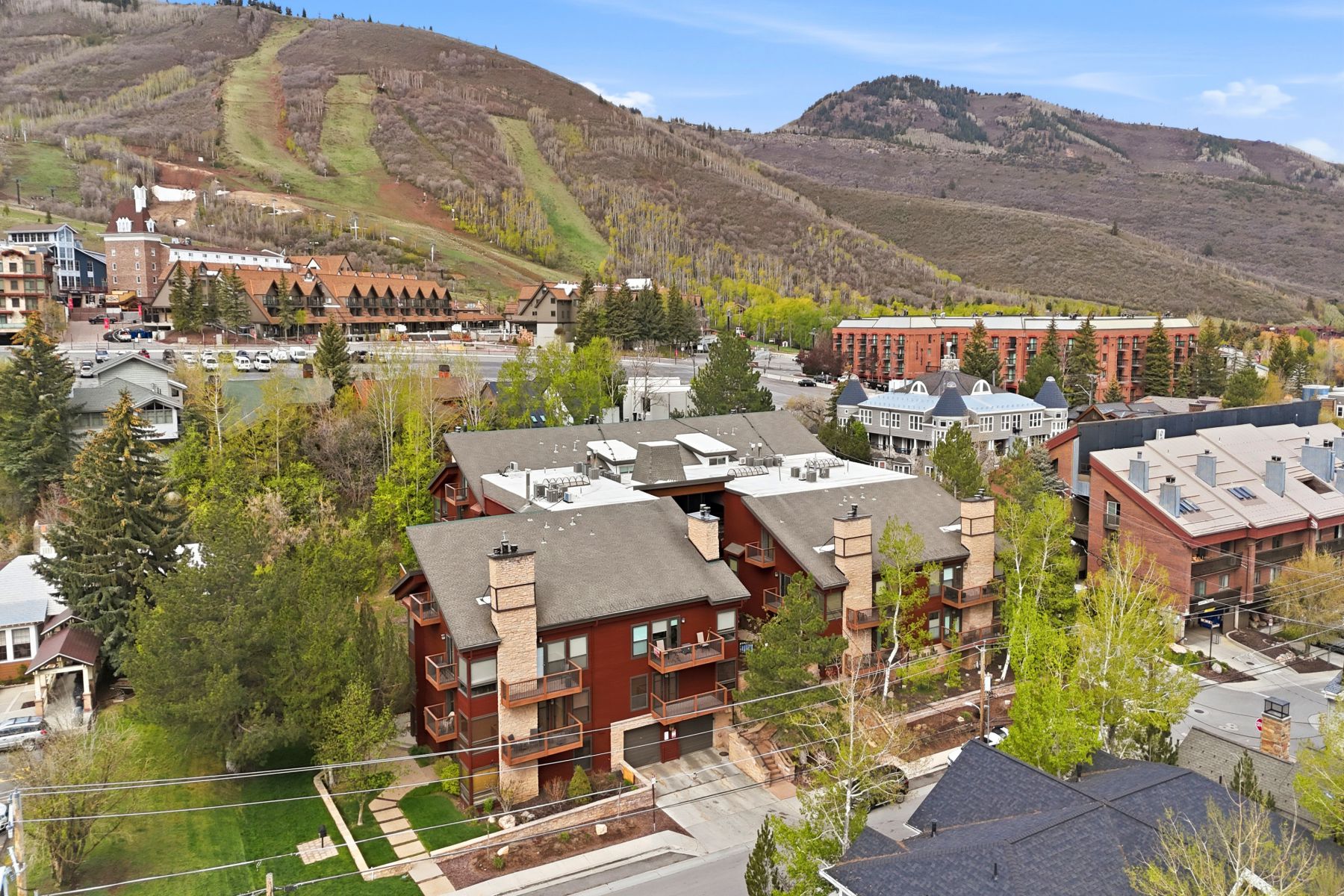 Multi-level architectural residences featuring red siding, stone chimneys, and private balconies