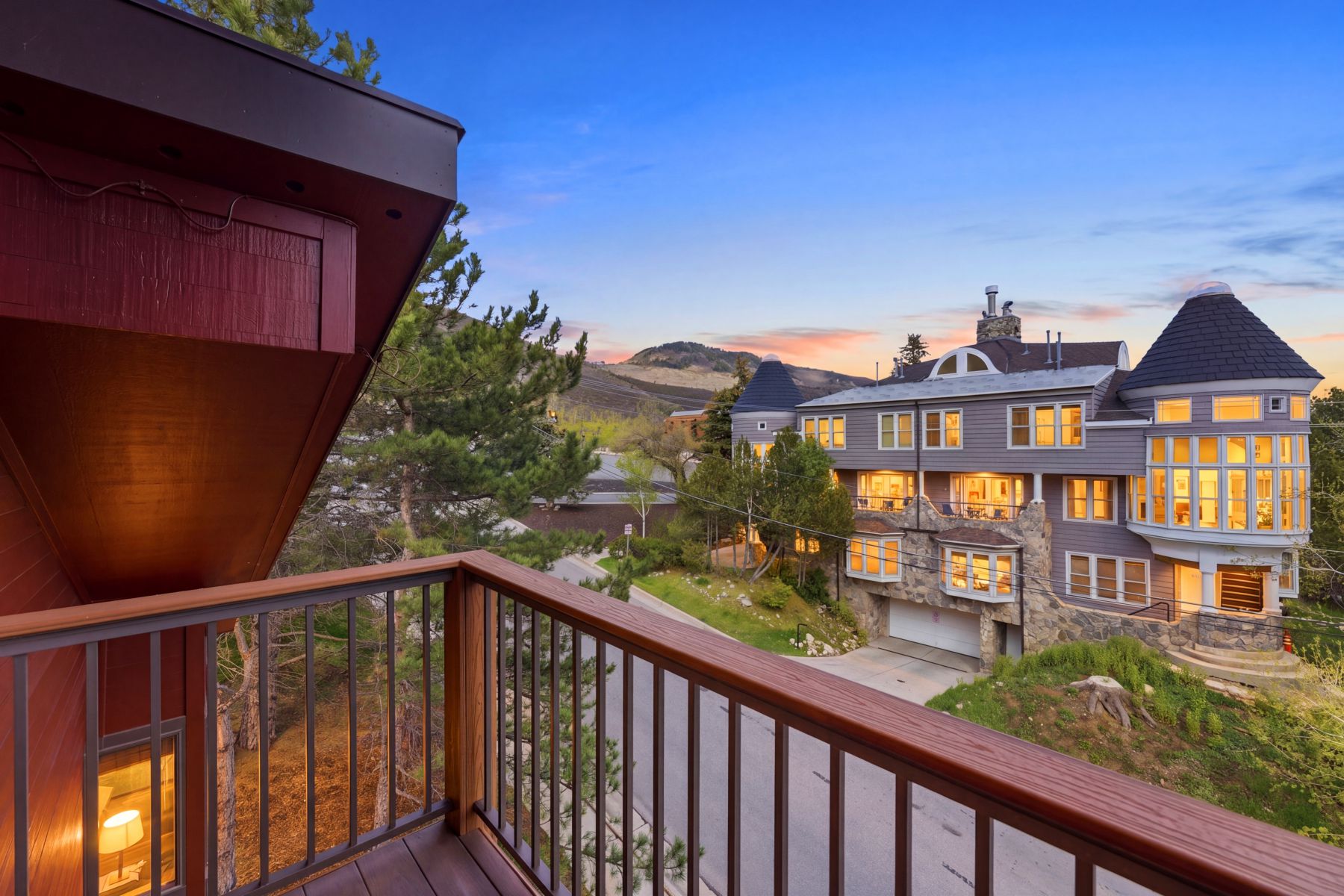 Balcony with wood-finish railing and metal spindles overlooking a multi-level residence
