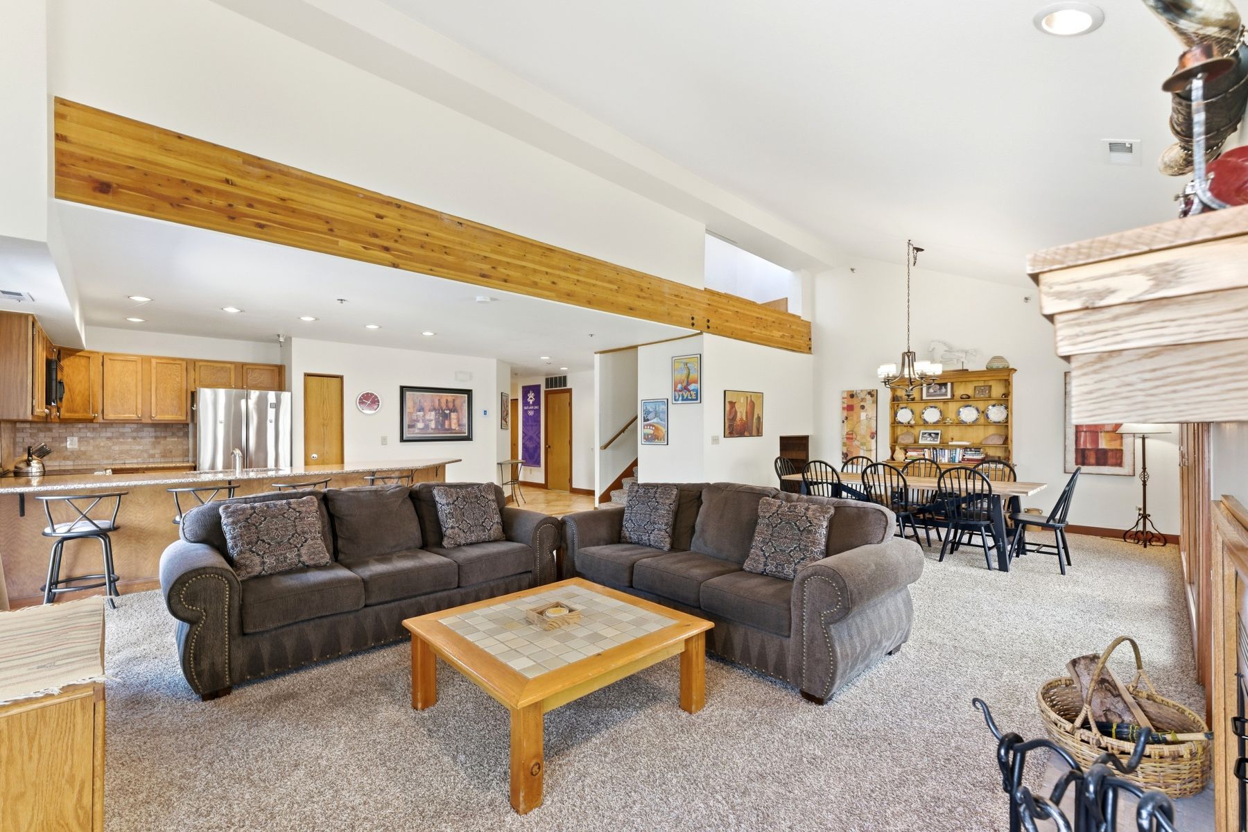 Open-concept living area featuring high vaulted ceilings with exposed wood beams