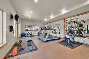 Spacious recreation room featuring recessed lighting, multiple windows, a wall-mounted television, and wood-trim accents