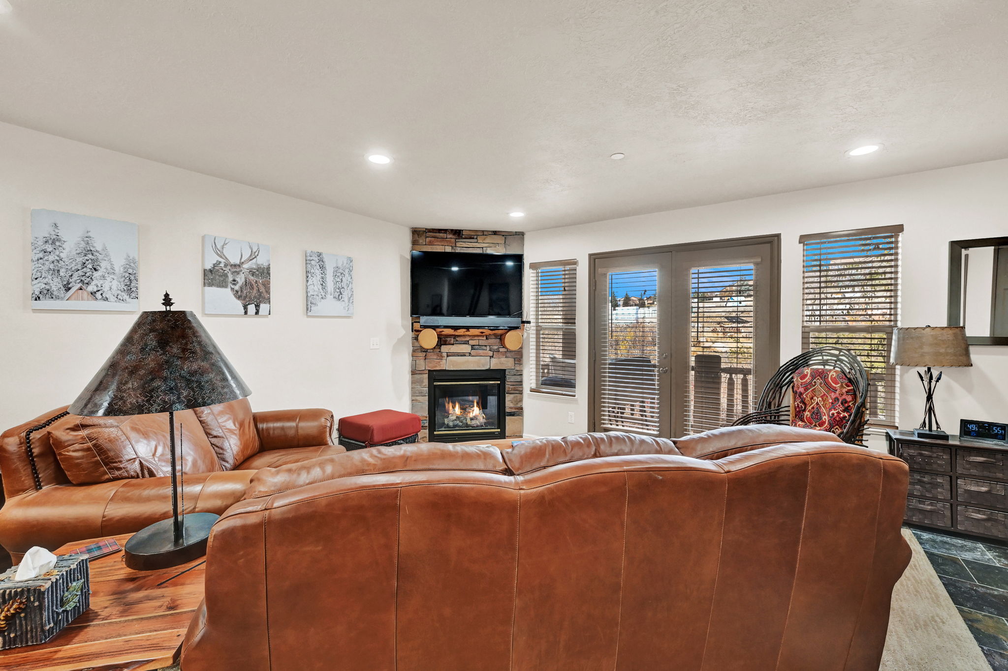 Living area featuring a stone-faced corner fireplace with a built-in television alcove, recessed lighting, and a slate-tile floor