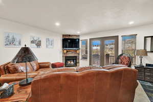 Living area featuring a stone-faced corner fireplace with a built-in television alcove, recessed lighting, and a slate-tile floor
