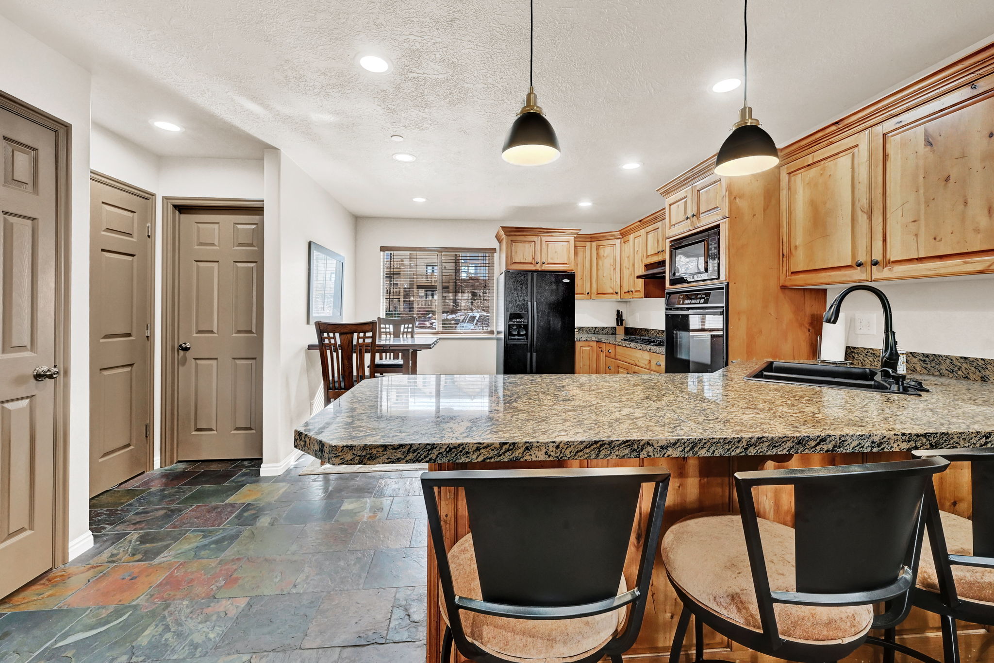 Kitchen featuring a breakfast bar with stone-finish countertop, wood cabinetry, and a built-in oven and microwave