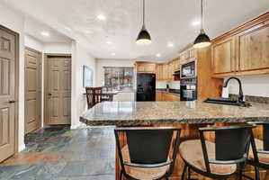 Kitchen featuring a breakfast bar with stone-finish countertop, wood cabinetry, and a built-in oven and microwave