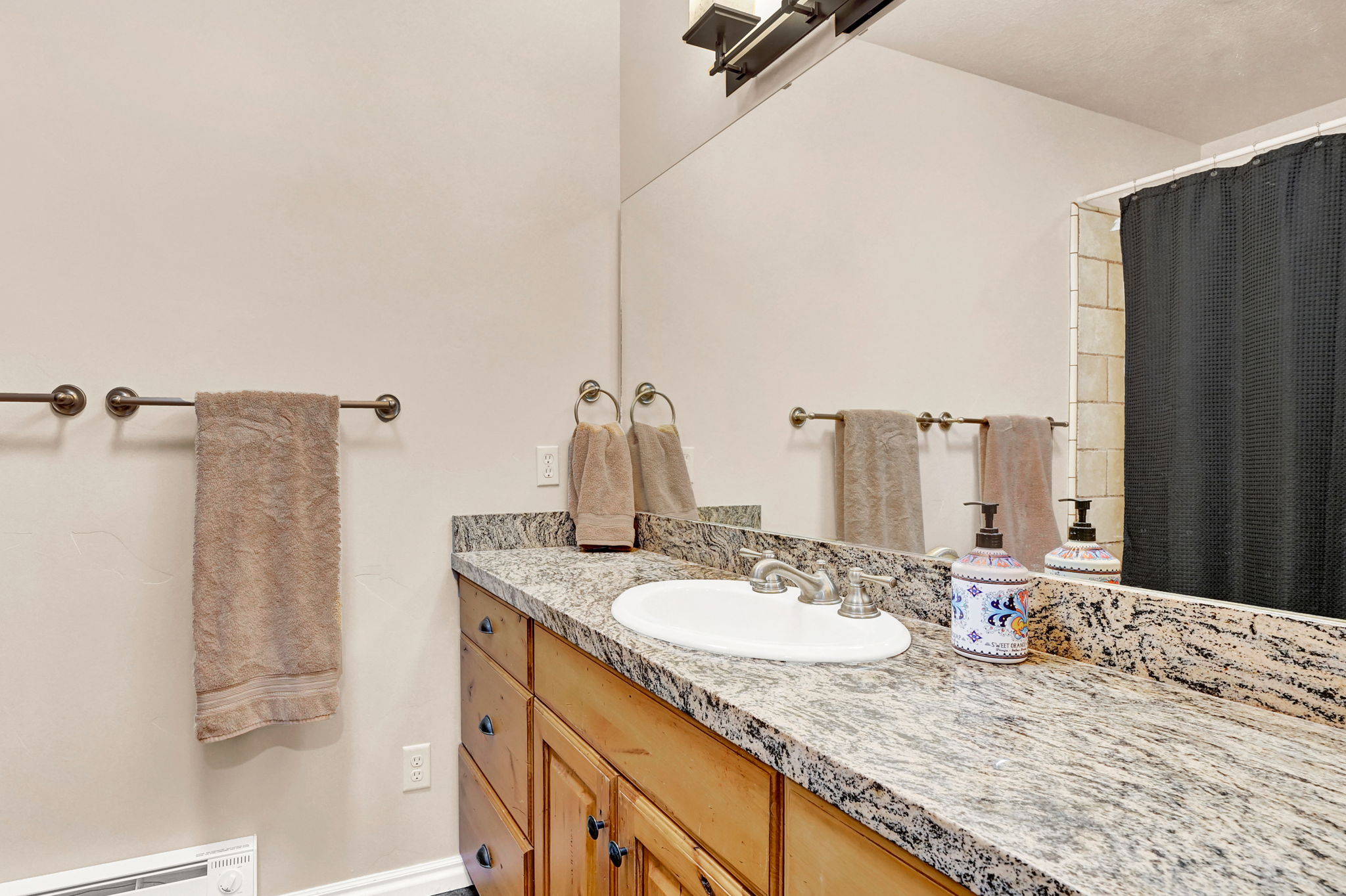 Bathroom vanity featuring a light-toned granite countertop with an undermount sink and brushed nickel faucet