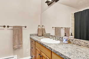 Bathroom vanity featuring a light-toned granite countertop with an undermount sink and brushed nickel faucet