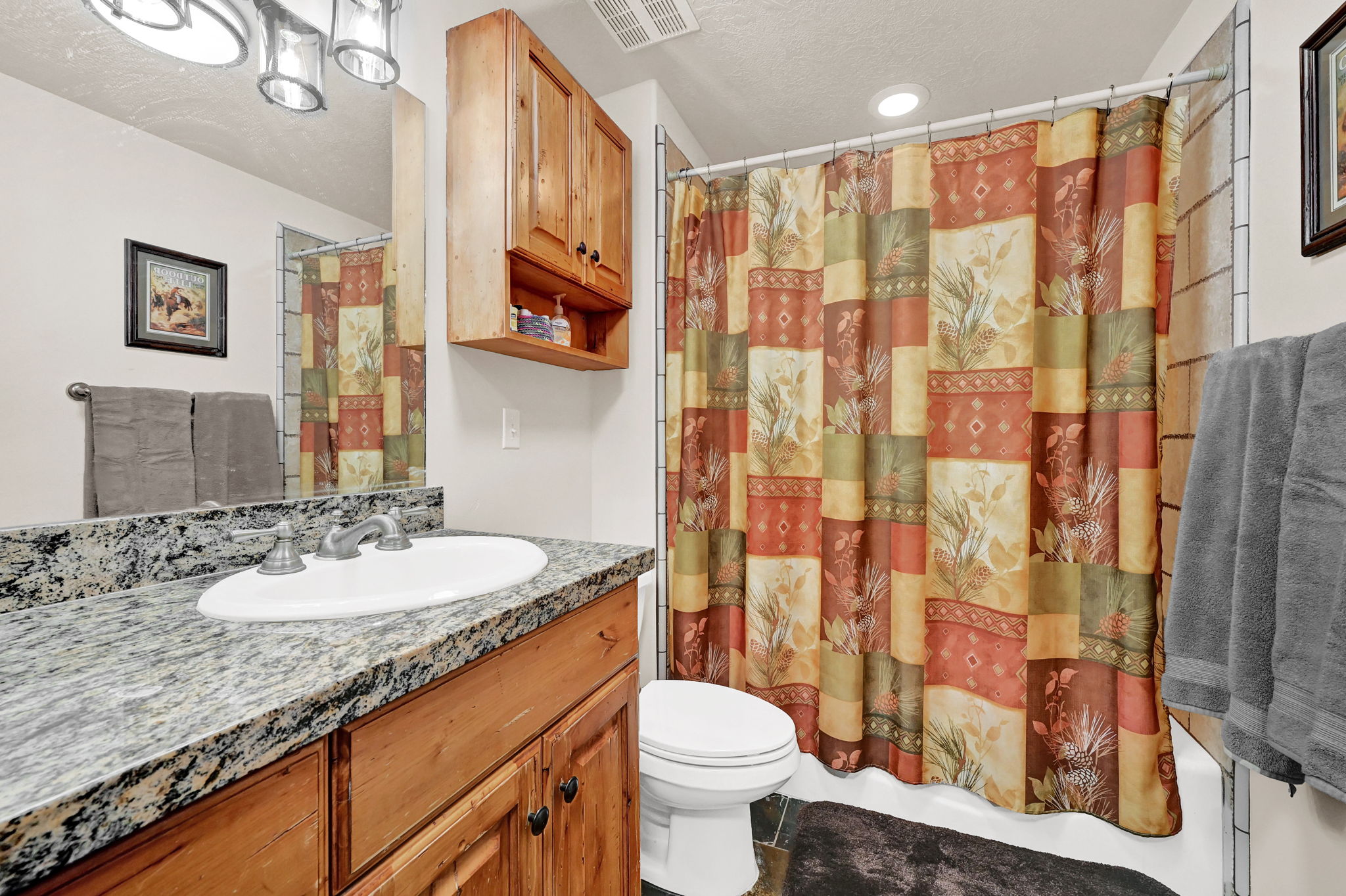 Bathroom featuring a wood-finish vanity with a granite countertop, undermount sink, and a chrome faucet