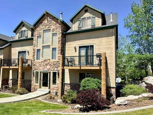 Multi-level condominium building featuring stone accents and light-colored siding