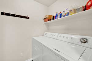 Dedicated laundry area featuring a white top-load washing machine, a white dryer, an upper storage shelf, and a wall-mounted coat rack