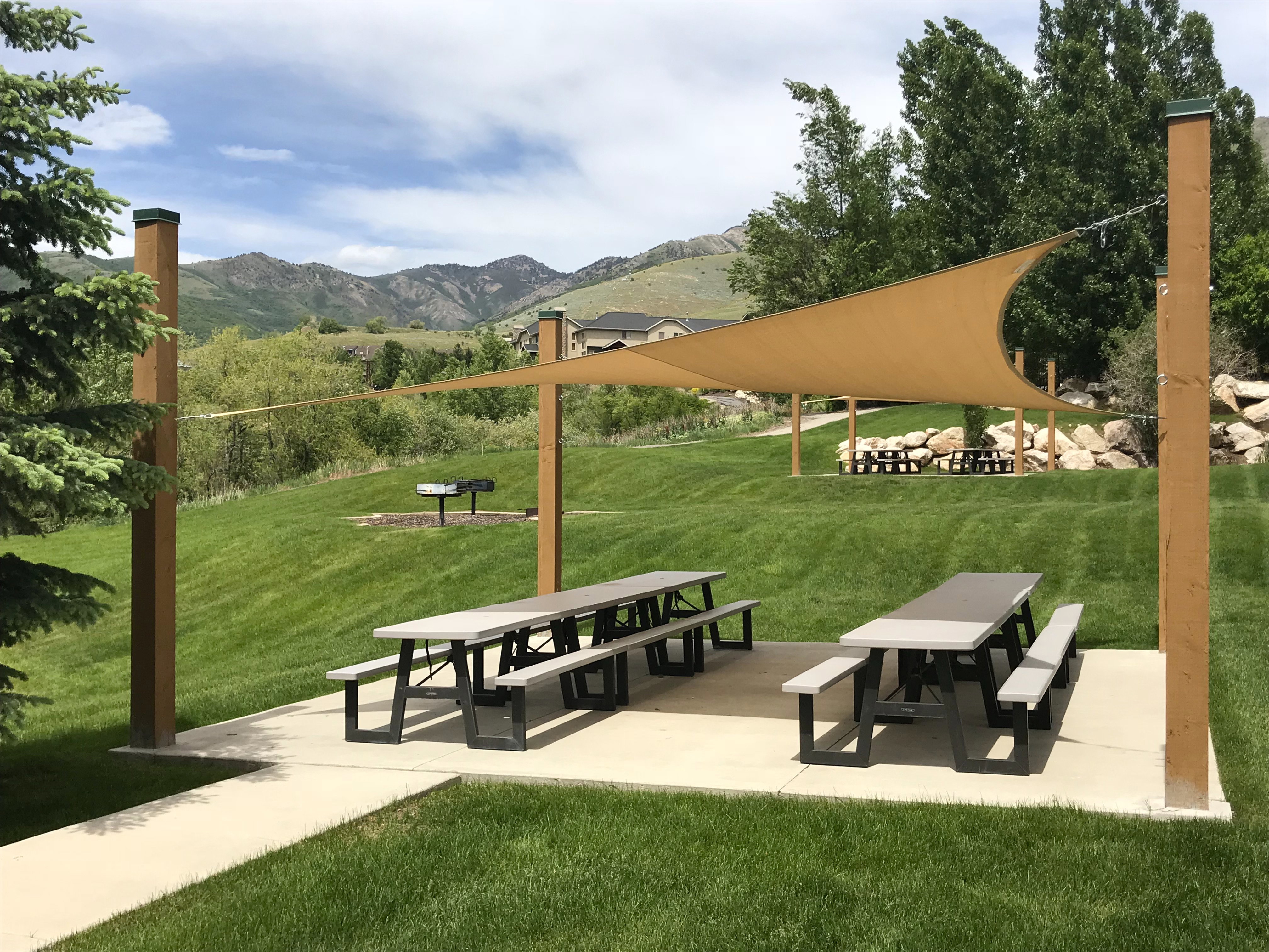 Outdoor recreation area featuring a shade sail structure over picnic tables