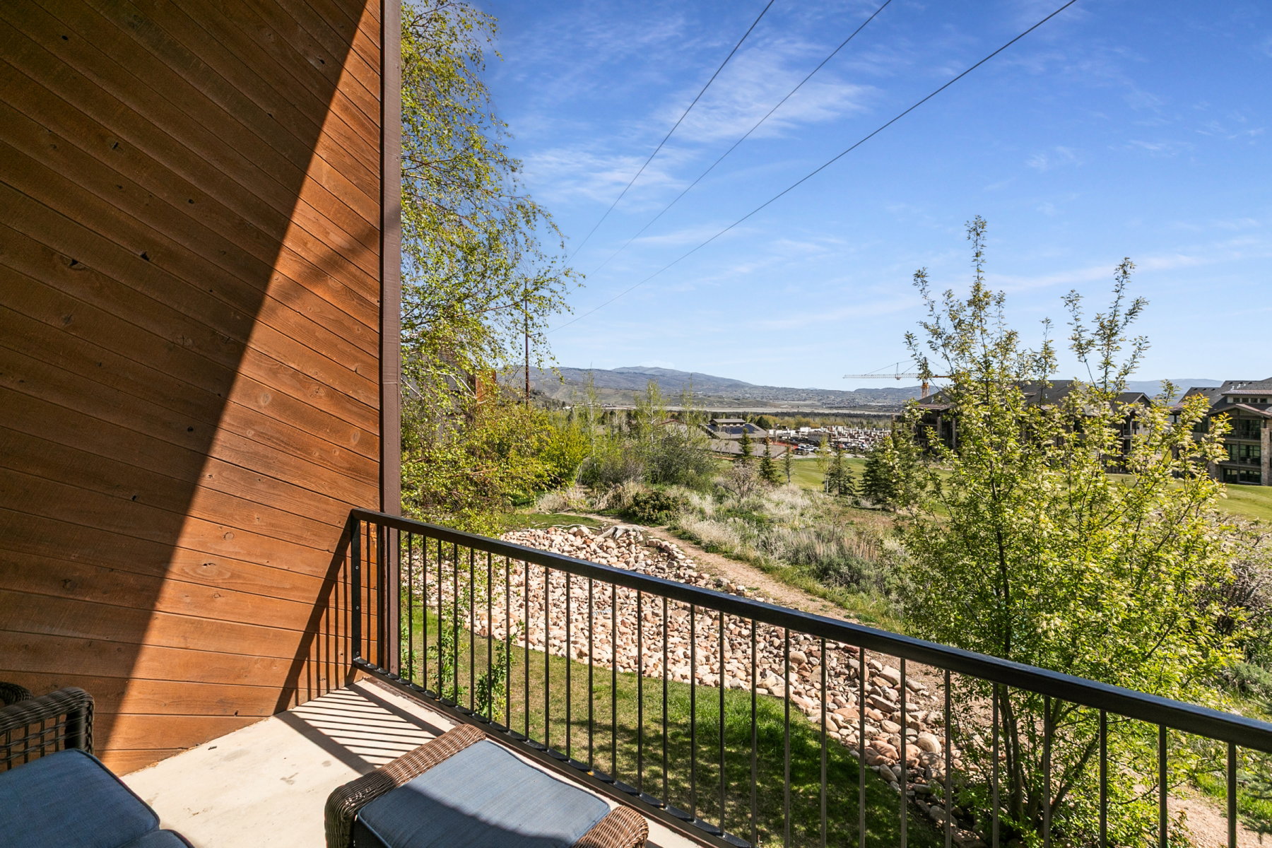 Private balcony with a metal railing, featuring composite wood siding and concrete flooring