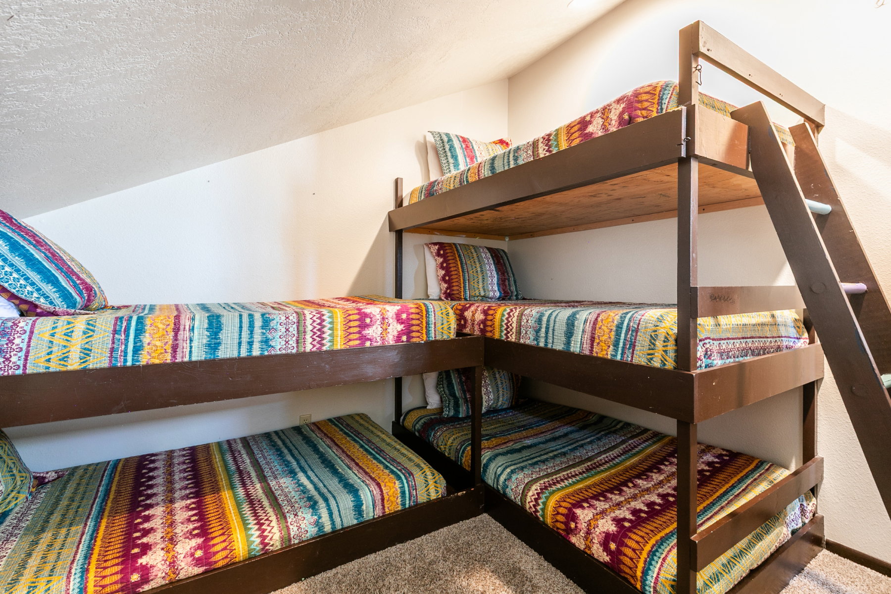 Built-in bunk beds with integrated ladders, painted brown wood frames, and an angled ceiling