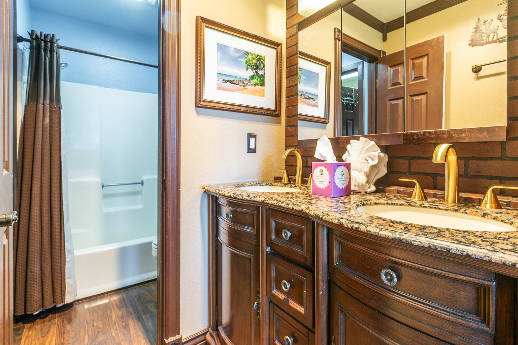 Double vanity featuring wood cabinetry with various storage drawers, a light-toned countertop, and gold-finish fixtures
